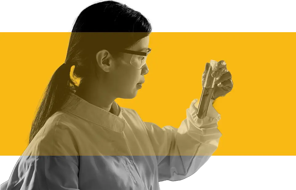 A woman in a lab coat holds a glass tube, focused on her scientific work in a laboratory setting.